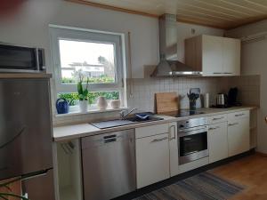 a kitchen with white cabinets and a window and a sink at Ferienwohnung mit Terrasse in Insheim +13 photos