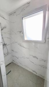 bagno con pareti in marmo bianco e finestra di Gîte cosy près de la mer - Maison familial tout équipé - Côte d'Albâtre a Cany-Barville Altre 13 foto