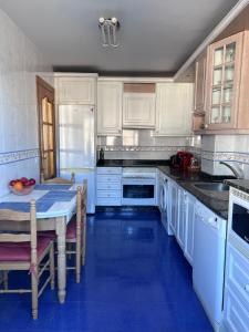 a kitchen with white cabinets and a blue floor at Casa la Plaza in Molinaseca