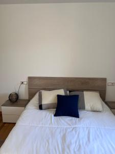 a bedroom with a large white bed with blue pillows at Casa la Plaza in Molinaseca