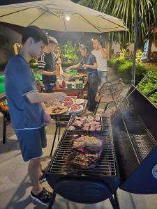 a group of people cooking food on a grill at Sweet Garden Homestay in Xuân Sơn