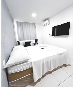 a white room with a table and a tv at Brisa do Mar Apartments in Fortaleza