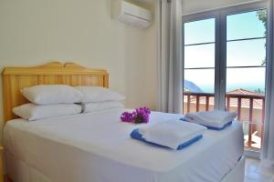 Una cama blanca con almohadas blancas y flores púrpuras. en Villa Zeytin Kalkan, en Kas 29 fotos más