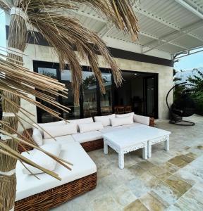 a patio with white couches and a palm tree at Villa Aora Bingin Large 4 Bedroom Villa in Uluwatu