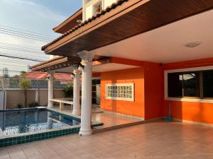 a house with a swimming pool and an orange wall at 中天海滩桔子别墅 jomtien color villa in Jomtien Beach