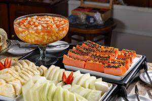 a table topped with plates of food and fruit at Park Tower Campinas Residence by Nacional Inn in Campinas