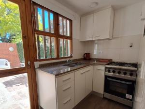 Una cocina con gabinetes blancos y un horno de estufa. en Duplex BESUGO, con patio y parrilla, en Pinamar