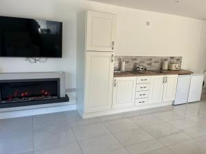 a kitchen with a fireplace and a tv on the wall at The Bleach Green Cottage in Drumahoe