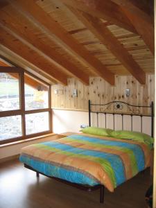 Cama en habitación con techo de madera en Casa de Montaña Alto Curueño, en Lugueros