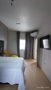 a bedroom with a white bed and a window at Quarto Belíssima in Pelotas
