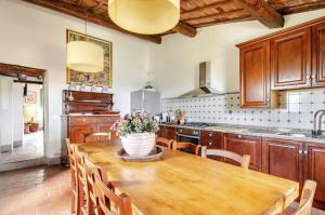 a kitchen with a wooden table with a vase of flowers on it at Villa Il Poggio in Greve in Chianti