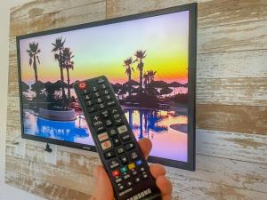 a person holding a remote control in front of a television at Refúgio Pousada Fortaleza in Fortaleza