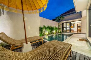 a patio with chairs and an umbrella next to a swimming pool at Lecatica - Brand New 2BDR Paradise Villa with Expansive Pool - Your Dream Retreat in Canggu! in Seminyak