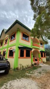 a green and orange house with a car parked in front at Daydream Hostel in San Juan