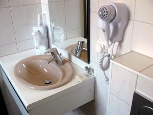 a bathroom sink with a hair dryer next to a mirror at Hotel-Restaurant Zur Kanne in Schifferstadt