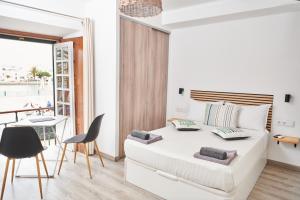 a white bedroom with a bed and a table and chairs at Taah Billa Guest House in Tavira