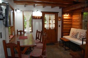 a dining room with a table and chairs and a couch at La Cabañita in San Martín de los Andes
