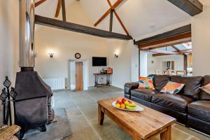 a living room with a leather couch and a wood stove at Castle Forge 4-Bedroom Historic Purbeck Forge in Kingston, Corfe Castle, Sleeps 7 in Kingston