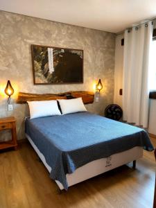 a bedroom with a large bed with a blue blanket at Casa da Prainha Lapinha da Serra in Santana do Riacho +28 photos