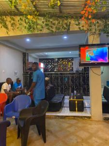 un hombre parado en una sala de estar con TV en Jeymax Hotel and Suite, en Ogijo