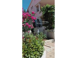 einen Garten mit Blumen und einem rosa Haus in der Unterkunft Apartments Marijana Zaboric in Zaboric