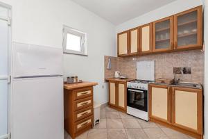 a kitchen with a white refrigerator and wooden cabinets at Apartment Lara in Tribunj