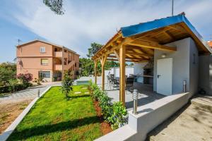 a backyard with a pergola and a house at Apartmani Savin in Brodarica