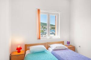 two beds in a bedroom with a window at Apartments Kukljica Ugljan in Kukljica