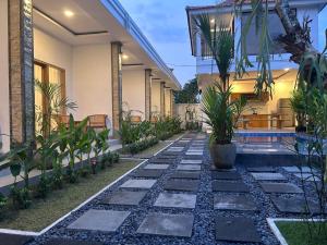 a walkway in front of a house with plants at Alit Guest House in Uluwatu
