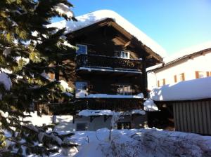 a building with a balcony in the snow at Silverbirch Chalet - Davos in Davos