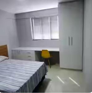 a bedroom with a bed and a desk and a yellow chair at Descanse no PARAÍSO DAS ÁGUAS II in Maceió