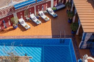 瓦尔扎扎特Le Petit Riad Maison d'hôtes的享有带躺椅的游泳池的顶部景致