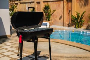 a barbecue grill sitting next to a swimming pool at Luxury Massarossa Pool Villa Pattaya-21 in Pattaya Central