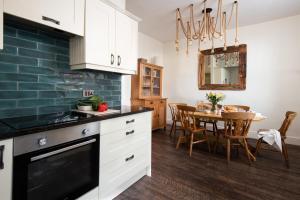 a kitchen with white cabinets and a dining room at Driftwood Cottage by Coast & Country Stays in Seahouses