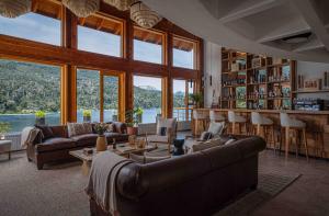 a living room with couches and tables and windows at Puerto Manzano Boutique Hotel in Villa La Angostura +75 photos