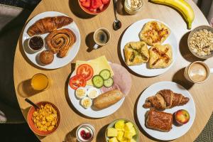 a wooden table with plates of breakfast food on it at Point A Hotel London Shoreditch in London
