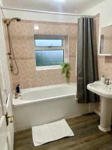 a bathroom with a bath tub and a sink at Spacious 4 Bed Home Near NEC, JLR & Airport Parking for 3 Cars Ideal for Contractors! in Olton