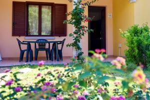 波尔托奥蒂罗卢ISA-Residence with swimming-pool in Ottiolu just 250 mt from the sea, apartments with air conditioning and private outdoor area的鲜花屋前的桌椅