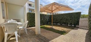 a patio with an umbrella and a table and chairs at L'Orchidée, 400m du lac & de la plage de Tanchet, 5 pers in Les Sables-dʼOlonne