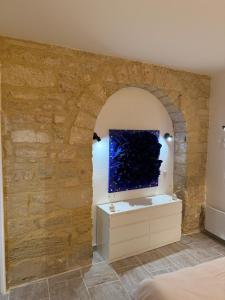 a room with a stone wall with a tv on a dresser at Magnifique , appartement de plain-pied avec jardin dans le centre in Uzès