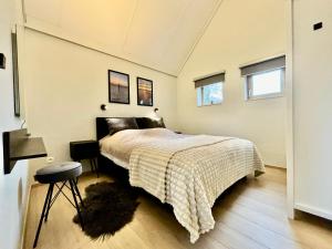 a bedroom with a bed and a stool and two windows at Vitamin Sea in Oostduinkerke