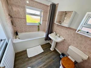 a bathroom with a tub and a toilet and a sink at Spacious 4 Bed Home Near NEC, JLR & Airport Parking for 3 Cars Ideal for Contractors! in Olton +27 photos