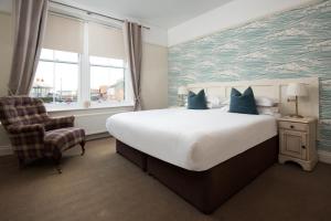 a bedroom with a large bed and a chair at Pebble Cottage by Coast & Country Stays in Seahouses