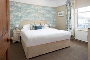 a bedroom with a large white bed with a blue patterned wall at Pebble Cottage by Coast & Country Stays in Seahouses