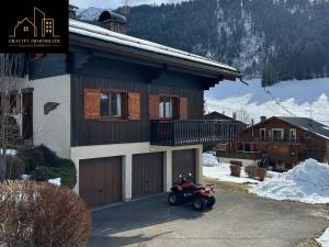 un motorino parcheggiato davanti a una casa nella neve di Triplex Exceptionnel à La Clusaz a La Clusaz