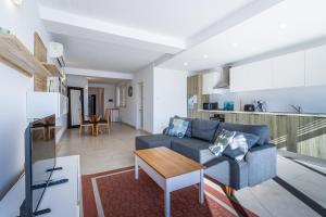 a living room with a blue couch and a table at Bright and modern apartment in St Julian's +8 photos