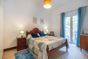 a bedroom with a bed with blue pillows and a window at VillaHouse in São Vicente