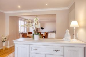 a white dresser with a vase of flowers on it at Ferienwohnungen Ziesing in Thale
