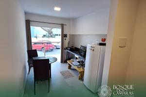 a kitchen with a refrigerator and a table with a chair at Ground Floor Flat in the Midst of Nature in Camaragibe