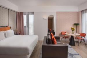 Pokój hotelowy z łóżkiem, kanapą i stołem w obiekcie NH Catania Centro w Katanii